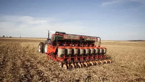 uma semeadora-adubadora de grande porte, modelo Planti Center PC-9/8, acoplada a um trator em plena operação d