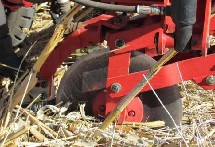 close-up detalhado de uma semeadora agrícola em plena operação no campo. O equipamento, com sua estrutura r