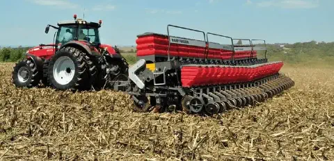 uma operação agrícola em pleno andamento, destacando um trator vermelho da marca Massey Ferguson, modelo de gr