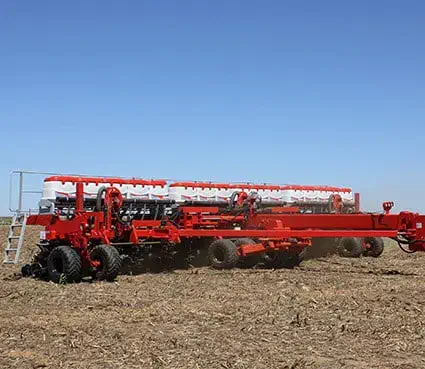 uma grande semeadora agrícola de cor vermelha em plena operação num campo. O equipamento, de alta capacidade,