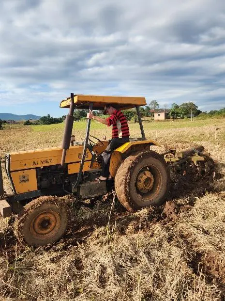 cena autêntica do trabalho no campo. Um agricultor, vestindo uma camisa listrada vermelha e preta, opera