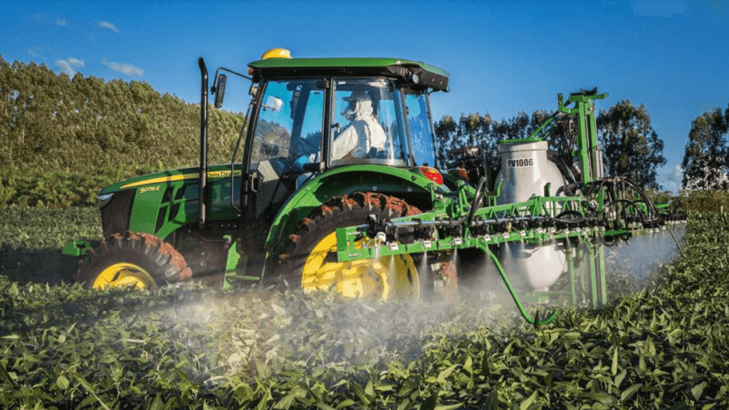 trator verde e amarelo da marca John Deere, modelo 5078E, em plena operação numa lavoura de cultura de port