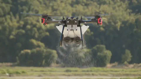 drone agrícola profissional em pleno voo, pairando a baixa altitude sobre uma lavoura. O equipamento, um