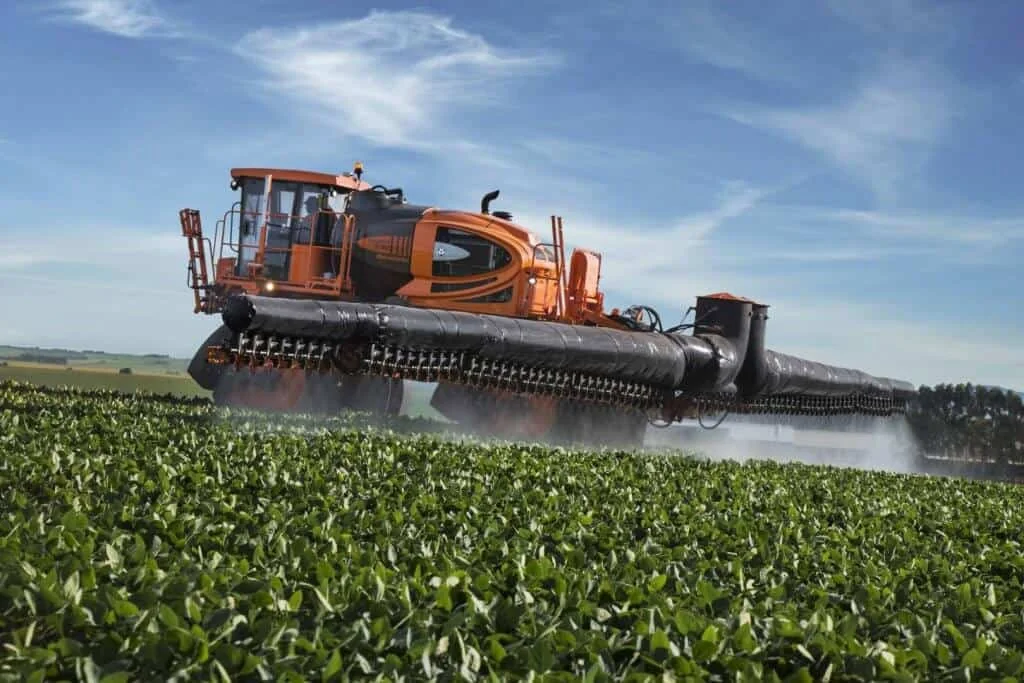 pulverizador autopropelido de grande porte, com um design moderno nas cores laranja e preto, em plena opera