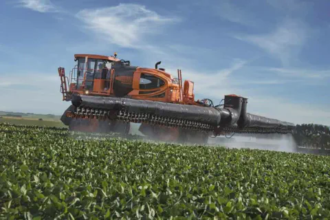 pulverizador autopropelido de grande porte, com um design moderno nas cores laranja e preto, em plena opera