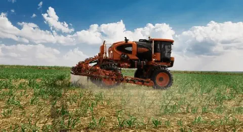 pulverizador autopropelido de grande porte, nas cores laranja e preto, em plena operação numa vasta lavoura