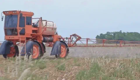 pulverizador autopropelido de grande porte, da marca Jacto e de cor laranja, em plena operação numa lavoura