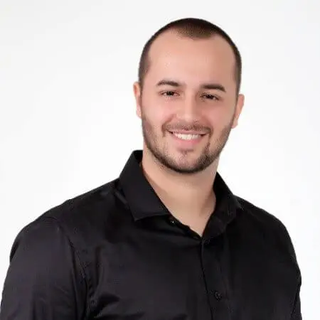 retrato profissional, estilo ‘headshot’, de um homem jovem, posicionado contra um fundo branco e neutro. Ele te