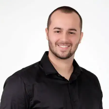 retrato profissional, estilo 'headshot', de um homem jovem, posicionado contra um fundo branco e neutro. Ele te