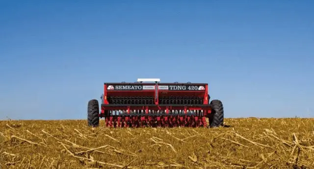 uma semeadora agrícola da marca Semeato, modelo TDNG 420, posicionada de forma centralizada em um campo recém-