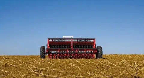uma semeadora agrícola da marca Semeato, modelo TDNG 420, posicionada de forma centralizada em um campo recém-