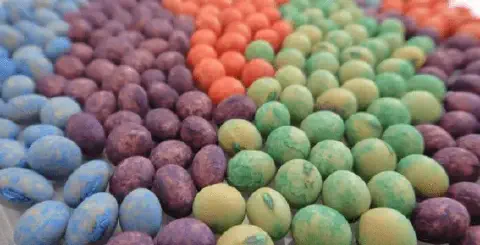 close-up de sementes, provavelmente de soja, que passaram por um processo de tratamento industrial. Elas es