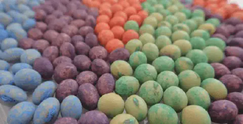 a close-up de sementes, provavelmente de soja, que passaram por um processo de tratamento industrial. Elas es