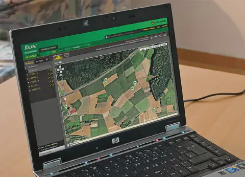 laptop HP aberto sobre uma mesa de madeira, com a tela mostrando a interface do software de telemetria agrí