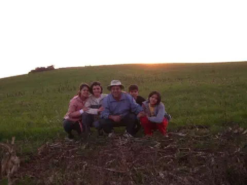 família de cinco pessoas – um casal e três filhos – agachados juntos em um campo verdejante, posando par