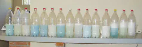 Teste de Garrafa: Evite Incompatibilidade na Calda Agrícola uma fileira de garrafas PET transparentes alinhadas sobre uma bancada, cada uma contendo uma quantidade de líq