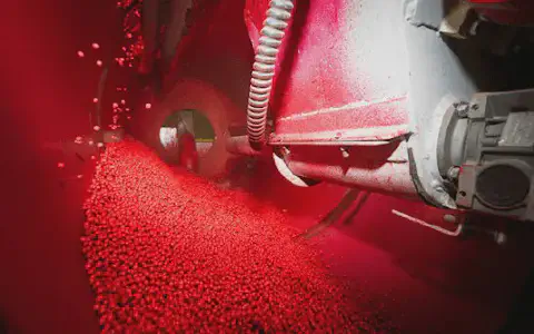 close-up do interior de uma máquina industrial durante o processo de tratamento de sementes. Milhares de pe