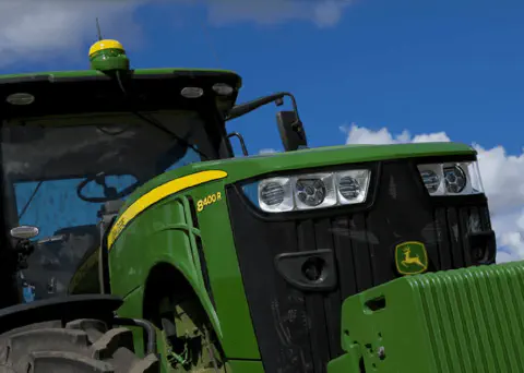 close-up imponente de um trator agrícola moderno, um John Deere modelo 8400 R, visto de um ângulo baixo que