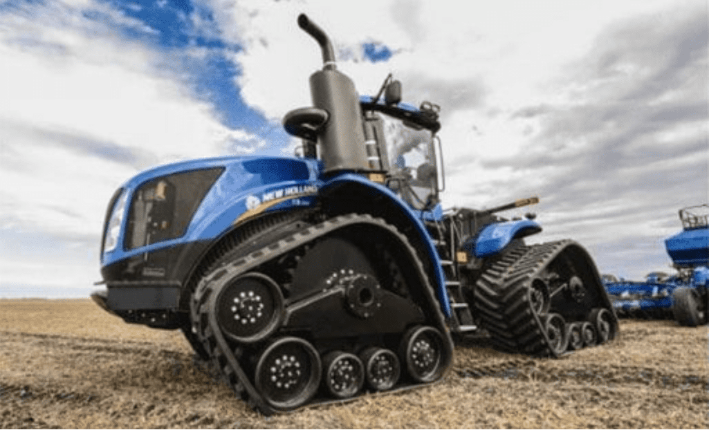 trator agrícola de grande porte da marca New Holland, na cor azul característica, em um campo aberto sob um