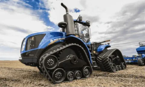 trator agrícola de grande porte da marca New Holland, na cor azul característica, em um campo aberto sob um