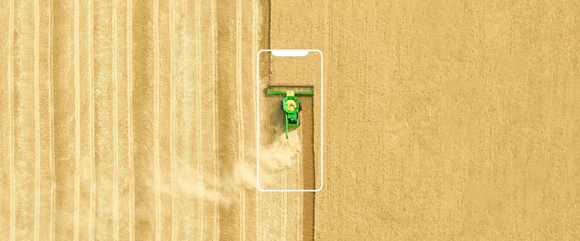 Vista aérea de um campo com plantação em operação de máquina agrícola, com ícone de celular sobreposto.