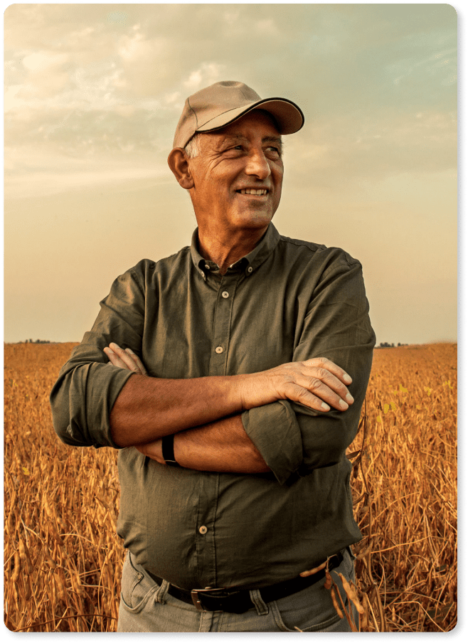 Produtor rural de boné e camisa sorrindo em sua fazenda.